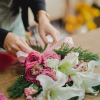 Florista realizando ramo de liliums blancos y rosas rosadas con verdes variados